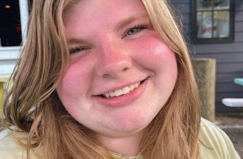 A closeup headshot of a smiling woman